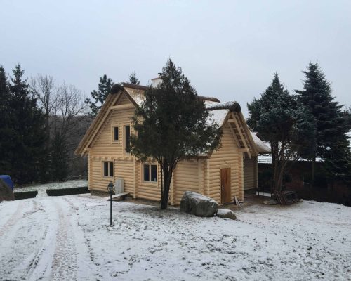 Dom z bali kryty strzechą.